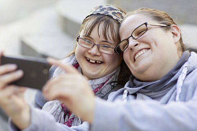 Zwei Mädchen schauen auf ein Handy und Lachen
